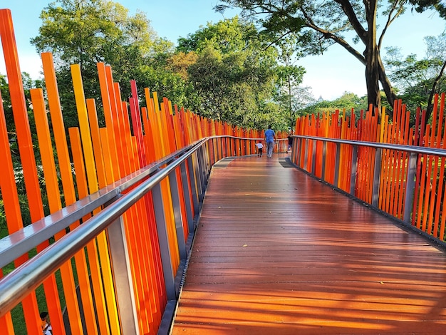 a wooden bridge with orange fence and a man walking across it.