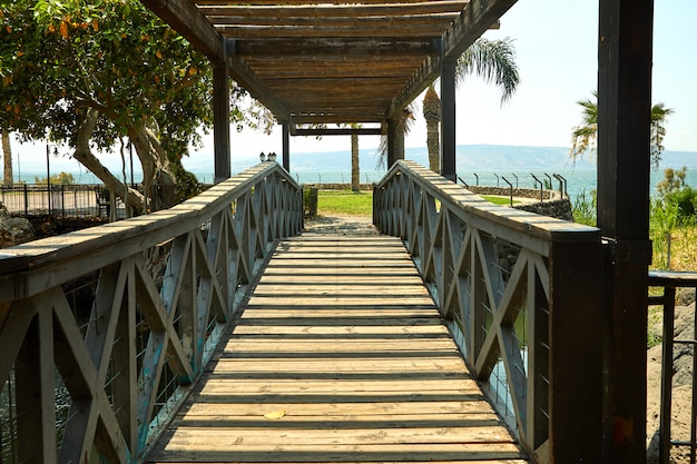 Wooden bridge with a roof on the Sea of Galilee, July