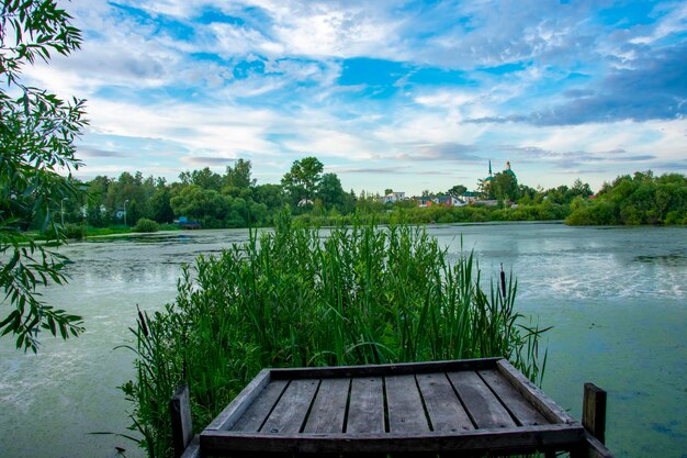 写真 木製の橋が葦の中に立ち、青い空を背景に夕焼けの後背地ロシア