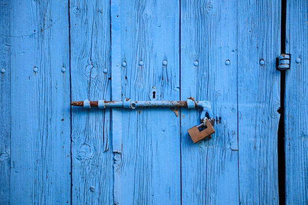 Wooden bright blue empty old door for background rusty latch padlock close up banner details