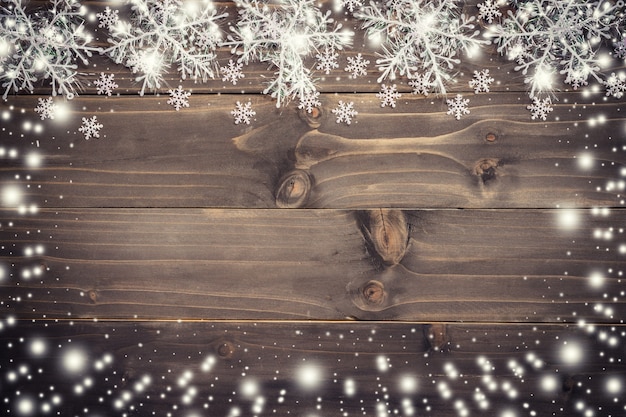 Wooden brown christmas background and snow white with snowflakes, copy space.