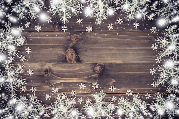 Wooden brown christmas background and snow white with snowflakes, copy space.