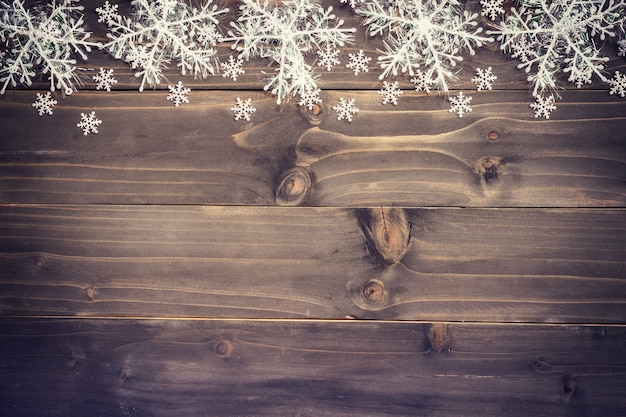 Wooden brown christmas background and white snowflakes with space.