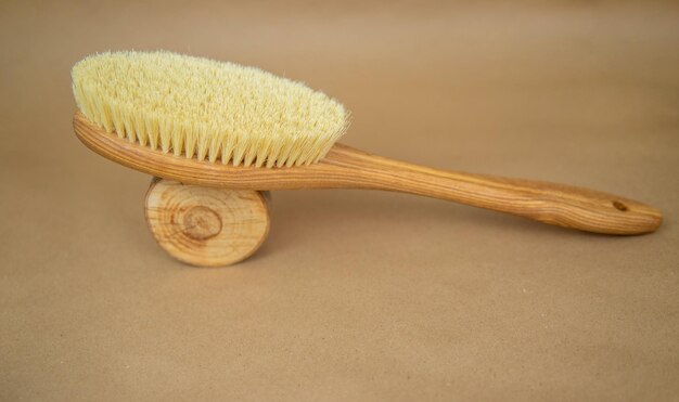 Wooden brush for dry body massage Anticellulite massage brush for body and legs on a beige background