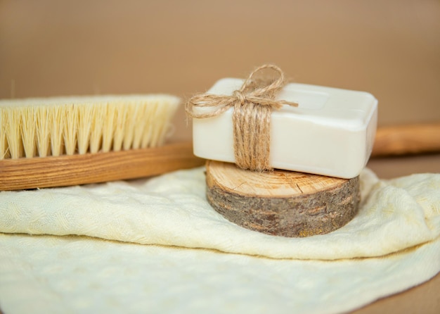 A wooden brush for dry body massage and natural soap lie on a towel Foot brush and pumice stone for heels