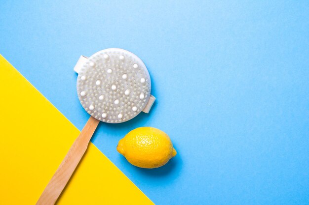 Wooden brush with natural cactus pile and lemon on a yellow and light blue background copy space