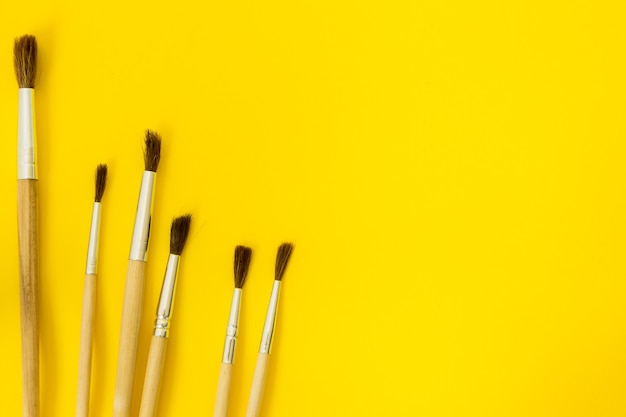 Photo wooden brushes for painting with paints on a yellow