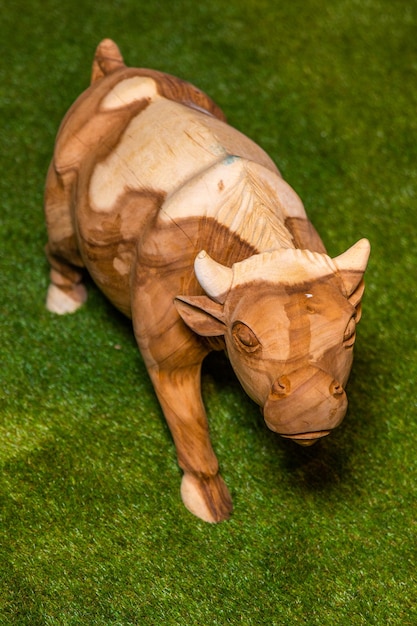 A wooden bull statue stands on a green grass field.