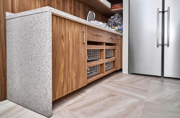 Wooden cabinet with drawer baskets and acrylic solid surface\
countertop in light food storage room