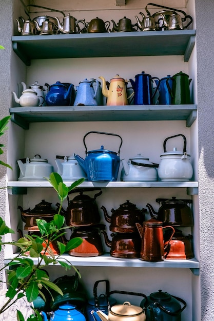 Wooden cabinet with shelves filled with blue metal teapots the
concept of rustic decor of a garden plot