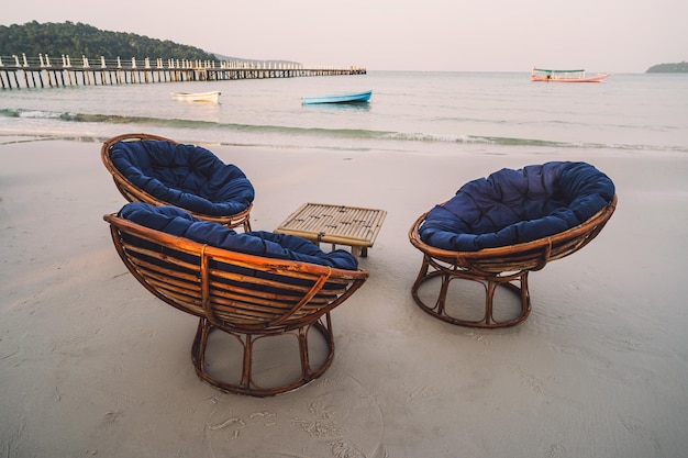 Wooden cafe table and chairs on a tropical beach with blue sea island Koh Rong Samloem Saracen Bay Cambodia