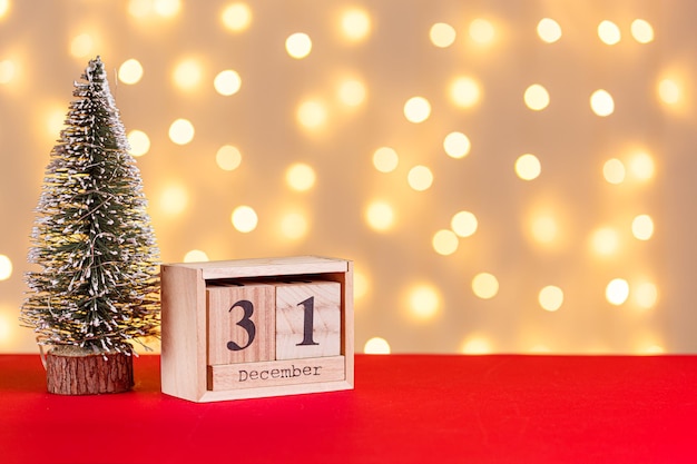 wooden calendar 31 december on red background and lights background close up