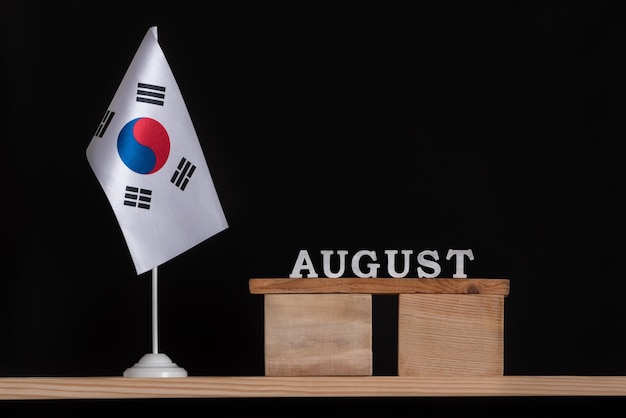 黒の背景に韓国の旗と8月の木製カレンダー。 8月の韓国の日付。