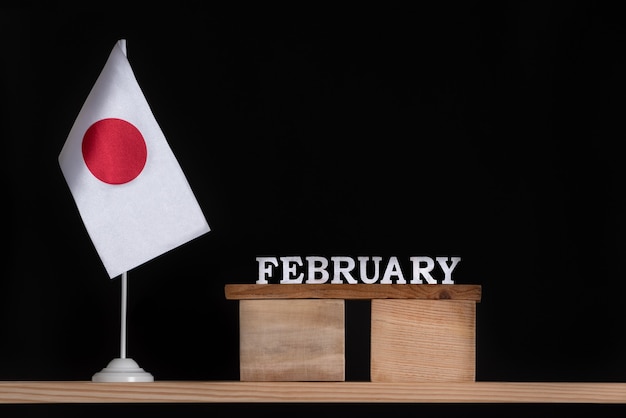 Wooden calendar of February with Japan flag on black wall