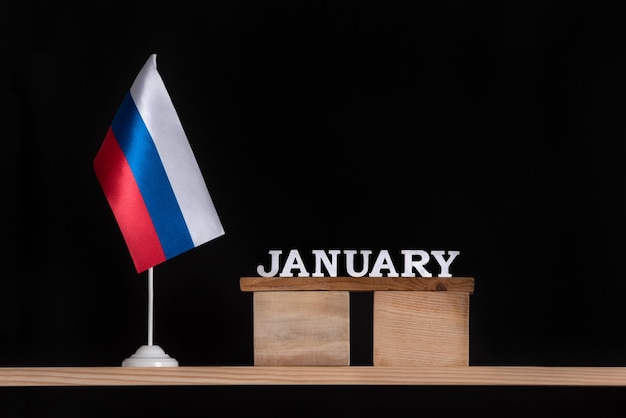 Деревянный календарь января с российским флагом на черном пространстве. Даты в России в январе.