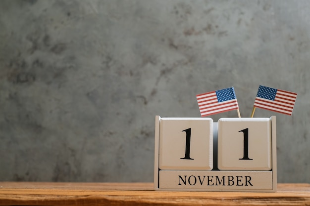 Foto calendario in legno dell'11 novembre con bandiere americane in miniatura. concetti di celebrazione della giornata mondiale dei veterani