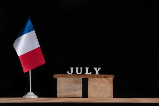 Деревянный календарь июля с французским флагом на черном фоне. праздники франции в июле.