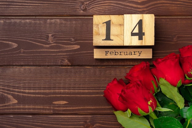 Wooden calendar and roses on brown wooden background