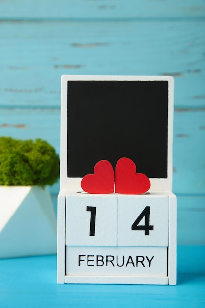 Wooden calendar with date of February 14 on blue background Valentine Day