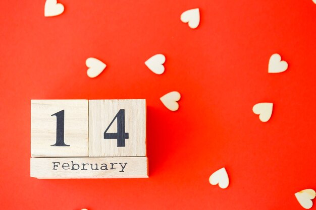 Photo wooden calendar with the date of february 14 on a bright red background. romantic date. valentine's day concept. top view, copy space.