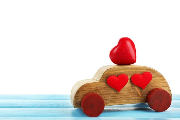 Wooden car with little red hearts on blue wooden table