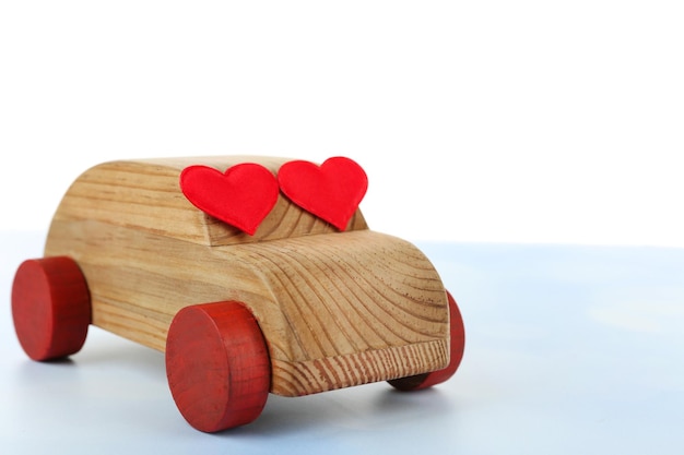 Wooden car with little red hearts over white background