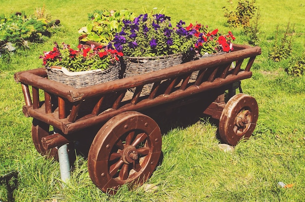 さまざまな色の花が咲く緑の芝生の上の木製カート