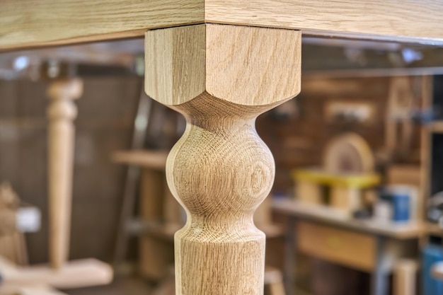 Wooden carved leg of solid oak of dining table in workshop extreme close up view