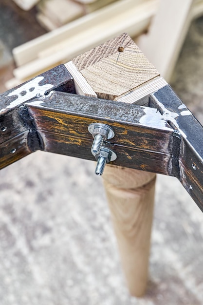 Wooden carved leg of solid oak with metal frame during manufacturing process of dining table