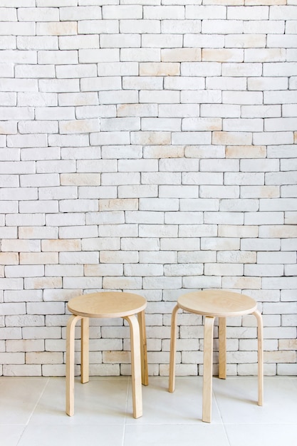 Wooden chair in empty white room against a brick wall