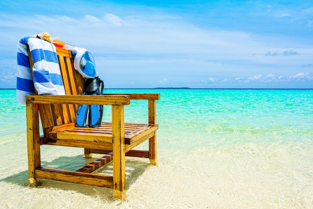 A wooden chair in the Indian Ocean with a towel shell flippers and inderwater mask