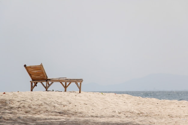 Sedia in legno sulla spiaggia di sabbia per il concetto di estate