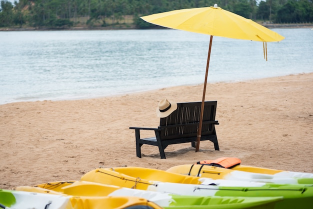 Фото Деревянный стул с желтым зонтиком на пляже.