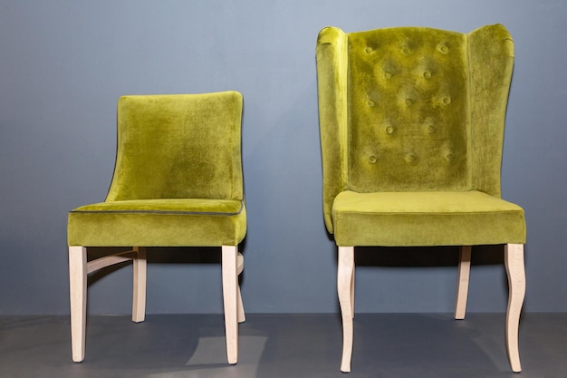 Wooden chairs with green upholstered near grey wall