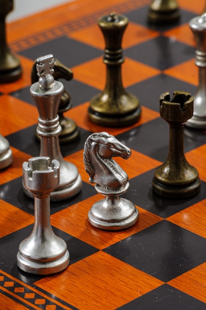 Wooden chess board with metal pieces. Checkmate.