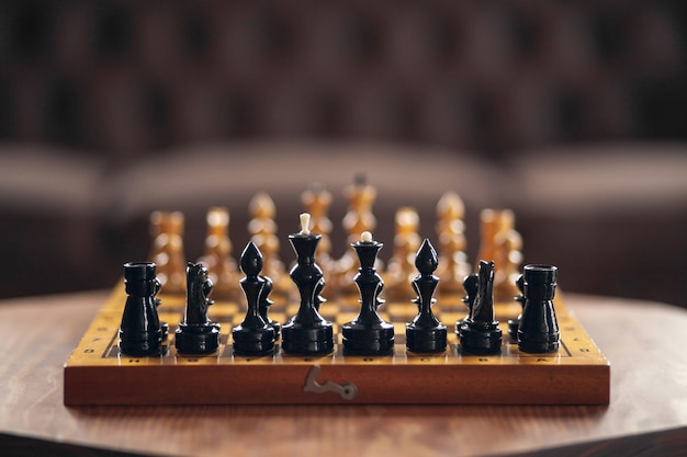 Wooden chess pieces on a board game, on vintage table, selective focus.