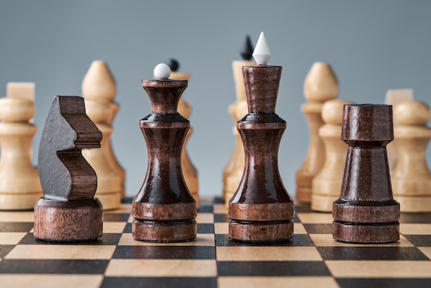 Wooden chess pieces on a chessboard, black pieces in a row, white pieces in the background, concept, strategy, planning and decision making