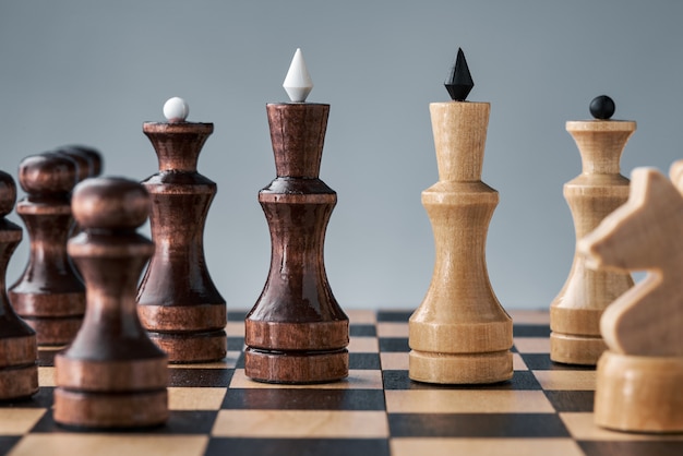 Wooden chess pieces on a chessboard, the confrontation of the white and black kings, the concept of strategy, planning and decision-making