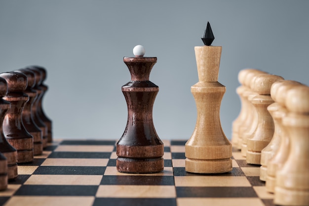 Wooden chess pieces on a chessboard, the confrontation of the white king and the black queen, the concept of planning and decision-making