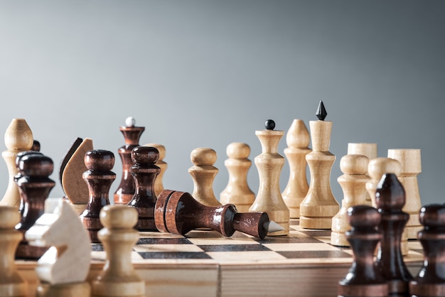 Wooden chess pieces on a chessboard, the confrontation of the white pawn and the black queen, planning and decision-making concept