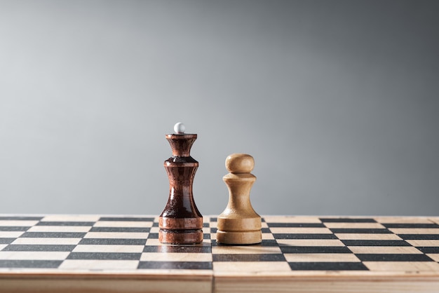 Photo wooden chess pieces on a chessboard, the confrontation of the white pawn and the black queen, planning and decision-making concept