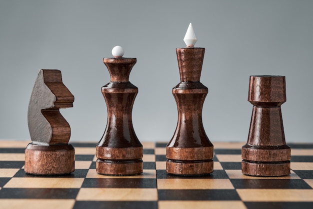 Wooden chess pieces on a chessboard, four black pieces in a row, concept, strategy, planning and decision making