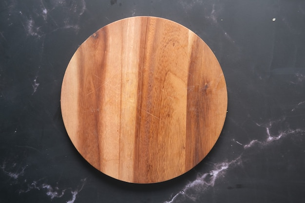 Wooden chopping board on black background top down