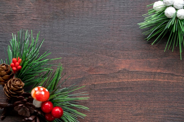 Фото Деревянная рождественская рамка из ели красной и зеленой с шишками на деревянном фоне скопируйте пространство рождества и нового года