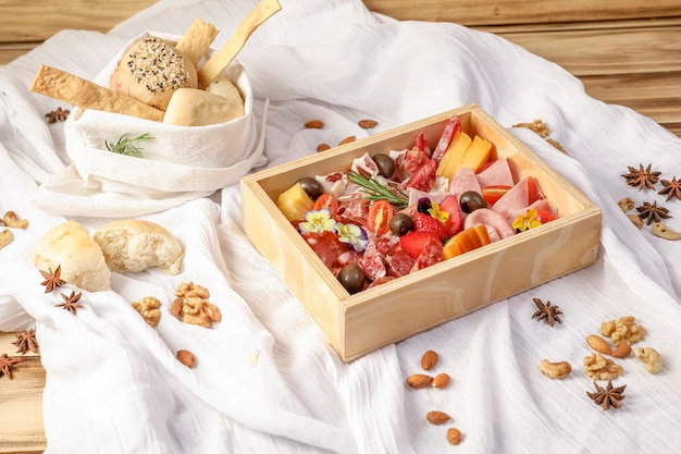 Photo wooden christmas gift box, with traditional italian implements: raw prosciutto, salami, parmesan cheese, olives and bread.