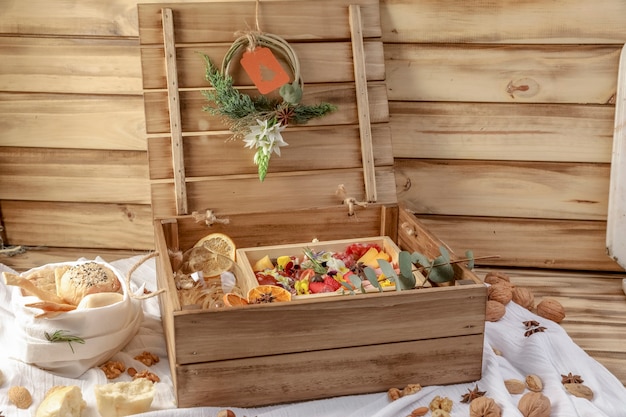 Photo wooden christmas gift box, with traditional italian implements: red wine and raw prosciutto, salami, parmesan cheese, olives and bread.