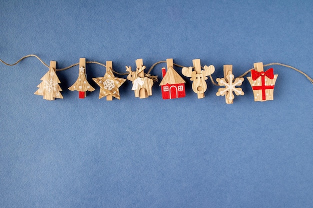 Wooden Christmas tree decorations on a rough rope on a blue background