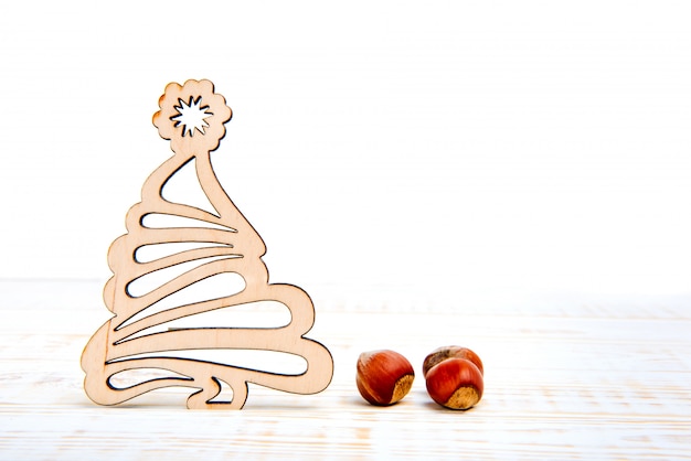 Wooden christmas tree and nuts on white background. Winter time. Empty space for text.