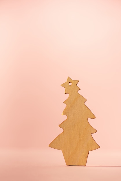 Wooden Christmas tree on pink background with copy space. New Year party.
