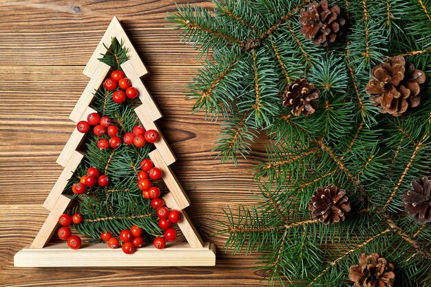 Wooden christmas tree with Fir branches inside decorated with rowan berries on a wooden background